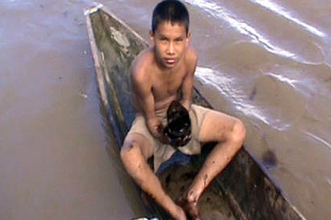 Un niño peruano manchado de crudo sobre una canoa. | GN.com