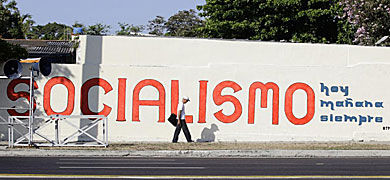 Un hombre camina junto a uno de los carteles que fomentan el socialismo.| AFP