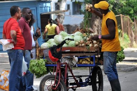 Varias personas con un vendedor ambulante en La Habana. | Efe