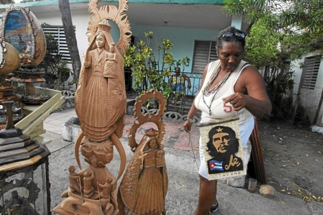 Una vendedora de imágenes de la Virgen del Cobre y de retratos del Che. | Efe