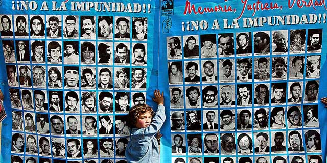 Un niño se apoya sobre un cartel con fotos de algunos de los 3.000 desaparecidos durante la dictadura de Pinochet en Chile | Afp
