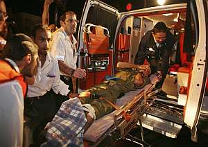 Miembros de los equipos de emergencias suben a uno de los soldados heridos a la ambulancia. (Foto: AP)