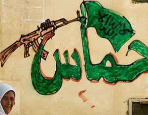 Una mujer pasa junto a un muro pintado con un grafiti de Hamas. (Foto: AP)