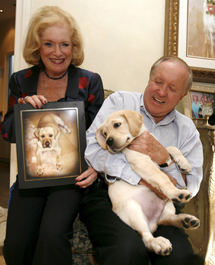 Nina y Edgar Otto posan con su labrador clonado, Sir Lancelot Encore, y una foto de su 'versión original' fallecida. | Efe