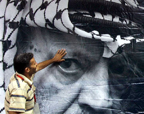 Un hombre coloca un cartel conmemorativo con la imagen de Arafat. | Efe Un hombre coloca un cartel conmemorativo con la imagen de Arafat. | Efe