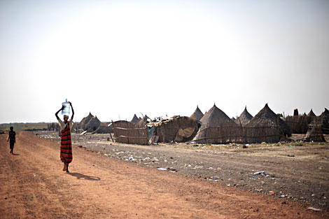 Una mujer sudanesa lleva un bidón de agua en la cabeza. | AFP