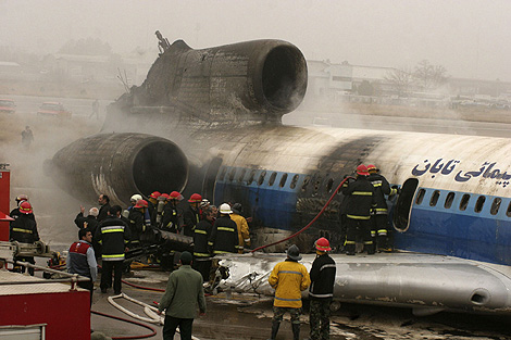 Los bomberos trabajan en la extinción del incendio en el avión estrellado en Mashad. | Reuters