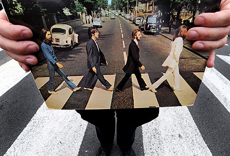 Un guía turístico sujeta una foto del disco 'Beatles Abbey Road' en la misma célebre calle londinense. | Andy Rain