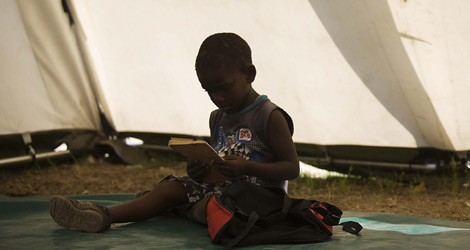 Un niño haitiano lee en una tienda de campaña usada como escuela. | Efe