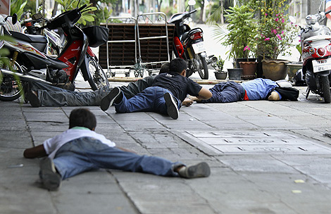 Tres hombres intentan repeler los disparos del Ejército en Bangkok. | Ap