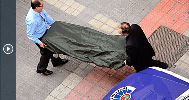 Dos operarios trasladan el cuerpo del fallecido en la agresión. | Efe