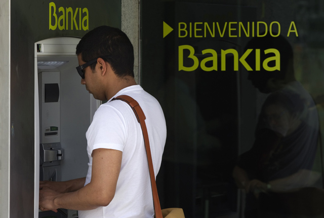 Un hombre saca dinero de un cajero de Bankia. | Reuters