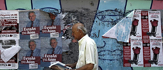 Finaliza la campaña electoral en Grecia. Un hombre camina con los cartes de fondo. | Efe