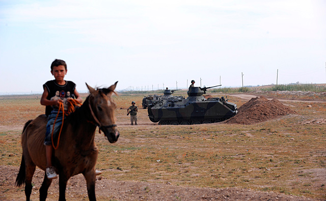 Un niño monta a caballo en Akçakale. Detrás suyo, militares turcos.| Afp