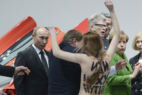 Una activista muestra su pecho desnudo a Putin y Merkel en Hannover. | Efe