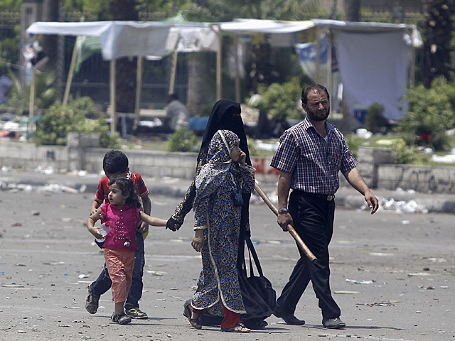 Un 'hermano musulmán', armado con un palo, y su familia en una calle de El Cairo. | Reuters