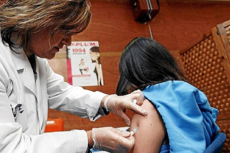 Una enfermera que vacuna a una menor de edad. | El Mundo