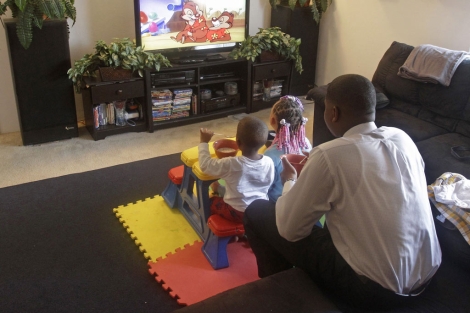 Un padre ve la televisión con sus hijos. | AP