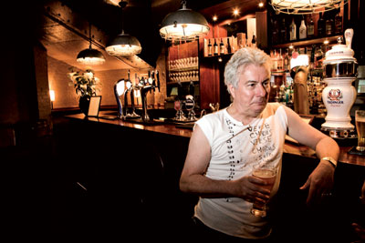Inglés convencional. Con camiseta sin mangas, Follet, de 59 años, se toma una cerveza en el bar Smithy’s, cerca del local de Charing Cross (Londres) donde ensaya con su banda de música.