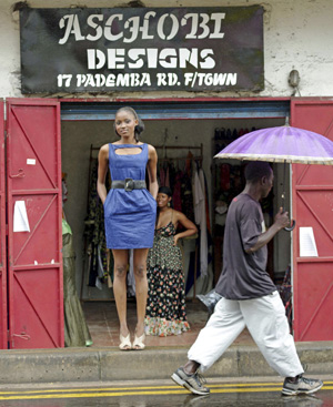 Ramatu Wuire, una de las reinas de la belleza de Sierra Leona, posa con los diseños de Adama Kai ante su tienda de Freetown. FOTO: REUTERS.