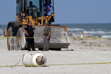 Dos agentes de policía observan la mina en la playa de Miami Beach. | AP