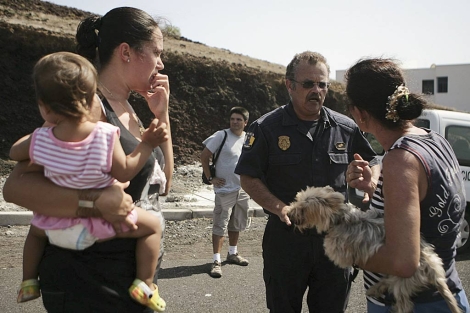 Un agente informa a vecinos de La Restinga sobre el punto de reunión. | Efe/Cristóbal García